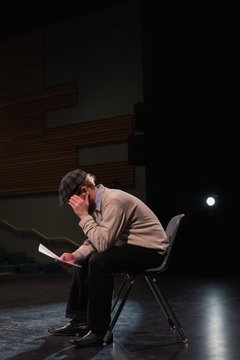Male actor reading script on stage