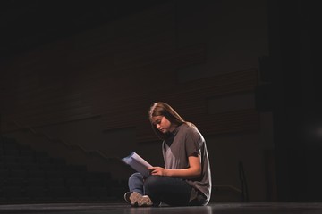 Female actress reading script on stage