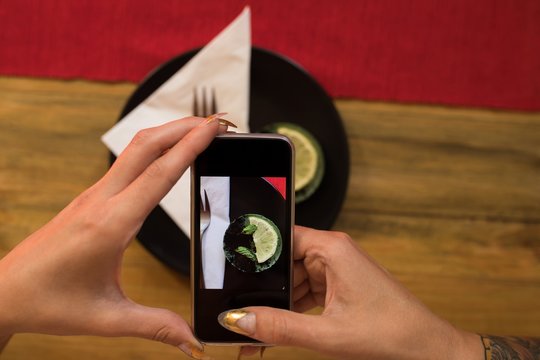 Woman clicking photo of breakfast with mobile phone