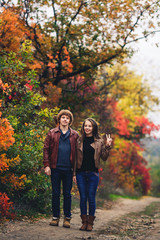 merry couple shows emotions. man and woman in leather jackets and jeans against background of autumn trees.