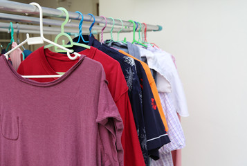 Obraz premium Closeup of purple T-shirt and others hanging on hangers for drying by sunlight. The simple way of life. 