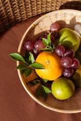 Bowl of fruit on the brown color background. Top view