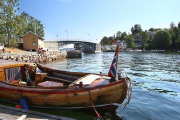 Obraz premium Oslo, Norway - July 22, 2018: Oslo harbor with bridge to Malmoya island in Oslofjord. Wooden boat in front of Malmoya island.