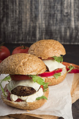 Fresh homemade burgers on wooden serving board. Metall background, selective focus, copy space. Glass of soda. 