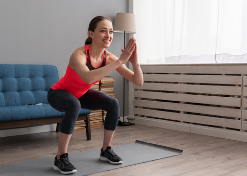 Happy fitness woman doing squat exercise at home