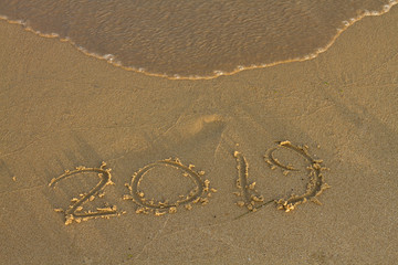 Fototapeta na wymiar Year 2019 written at the sand on a sea beach.