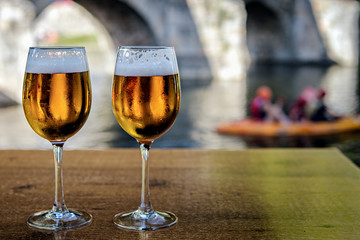 Chilled glasses of beer on outdoors bar table with natural background; focus on drinks.