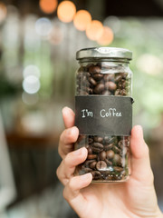 Coffee seeds in glass bottle in woman hand.