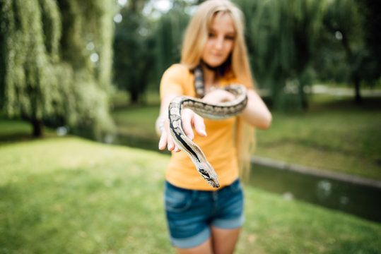 beautiful blonde girl is holding a snake in her hands. Contact the zoo.