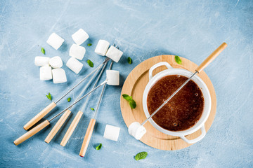 Chocolate fondue with marshmallow, winter party food, light blue background copy space