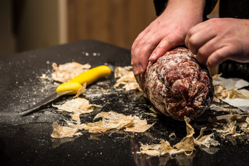 Chef removing salami casing close-up