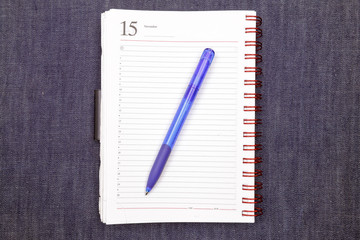 Notebook with pen on jeans texture