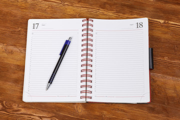 Top view notebook with pen on wooden table background