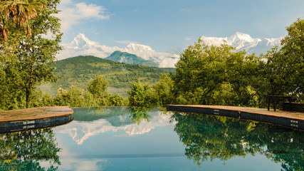 Naklejka premium Annapurna mountain range reflecting in an infinity pool in a resort, Pokhara, Nepal.