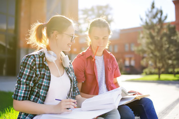 Young happy students with books and notes outdoors