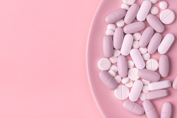 pills round and oval white and gray  on a pink background