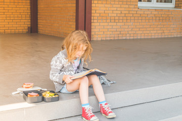 at recess at school girl, child out, at lunch with a book