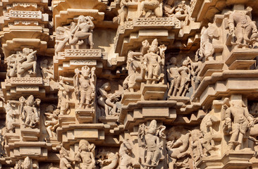 Indian architecture with figures of dancing people, gods, animals. Reliefs of historical temple in Khajuraho. UNESCO Heritage site, India.