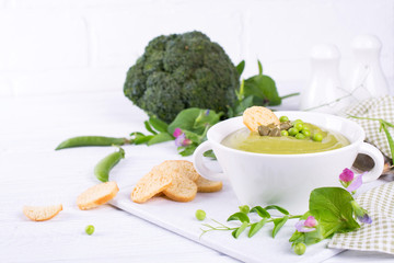 Vegetarian green cream soup of broccoli and green peas in bowl. On white background.