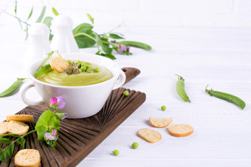 Light summer  delicious green peas cream soup served with pumpkin seeds,  croutons on white background.