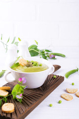 Light summer  delicious green peas cream soup served with pumpkin seeds,  croutons on white background. . Copy space
