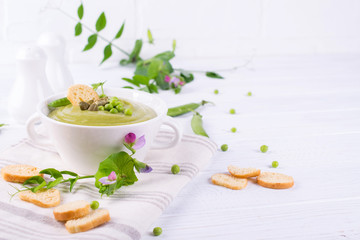 Bowl of  homemade green spring pea soup topped with pumpkin seeds,  croutons. On white background.. Copy space