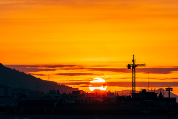silhouette of construction cranes at sundown