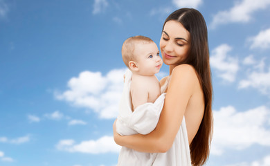 family and motherhood concept - happy smiling young mother with little baby wrapped into bath towel...