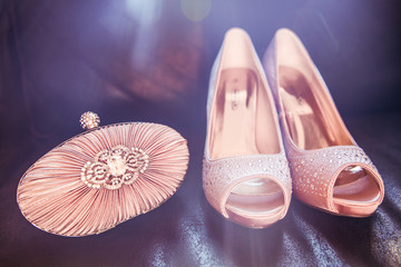 Diamond Encrusted Nude Colour Satin Bridal Clutch and Shoes on Dark Leather Sofa.