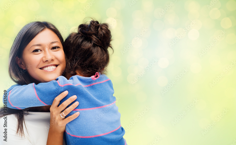 Wall mural family, motherhood and people concept - happy mother and daughter hugging over green holidays lights