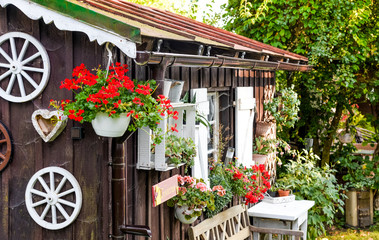 Fototapeta na wymiar Holzhütte Gartenhütte mit Blumen im Sommer Bayern