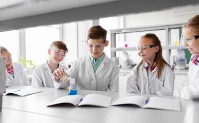 education, science, chemistry and children concept - kids or students with test tube making experiment at school laboratory