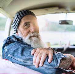 Portrait of an old hipster sitting in a van looking at camera