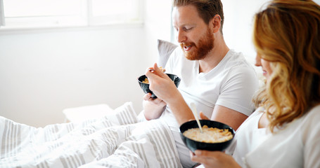 Young attractive couple having breakfast in bed