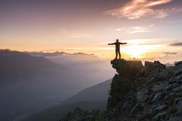 Young man standing on the Top of the mountain and enjoying total freedom during sunset in South...