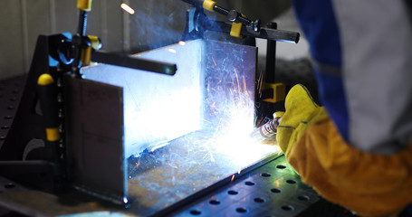 Worker cutting metalsheet by acetylene torch with bright sparks