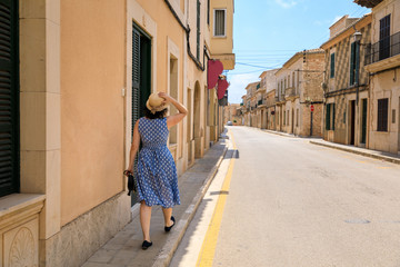 Woman is walking in the street of spanish town in summer