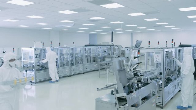 Sterile High Precision Manufacturing Laboratory where Scientists in Protective Coverall's Turn on Machninery, Use Computers and Microscopes, doing Pharmaceutics. Shot on RED EPIC-W 8K.