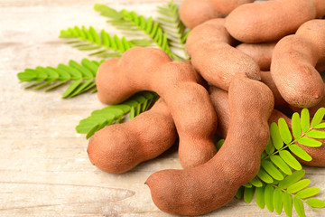 tamarind fruits and fresh leaves on the wooden board