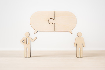 group of wooden businessman with jigsaw dialogue