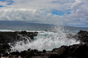 Wave crashing over the lava rock coastline of the island of Maui, Hawaii.