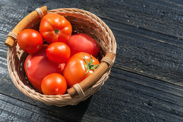 Ripe juicy red tomatoes on black wooden table