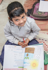  School girl in uniform of Indian Ethnicity sitting in their village classroom, looking at camera...