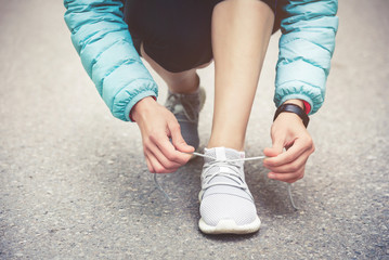 Girl runner tying laces for jogging her shoes on road in a park. Running shoes, Shoelaces. Exercise concept. Sport lifestyle. Vintage style