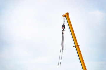 The top of a heavy mobile industrial yellow crane with lifting hook and cables