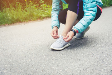Girl runner tying laces for jogging her shoes on road in a park. Running shoes, Shoelaces. Exercise concept. Sport lifestyle. Vintage style