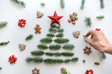 Creative idea for Christmas or New Year theme. A person makes a creative Christmas tree from fir branches and a star on top and is decorated with gingerbread cookies.