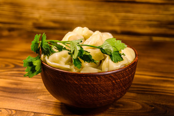 Fresh dumplings in ceramic bowl on wooden table