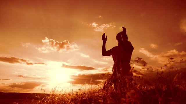 Girl folded her hands in prayer silhouette at sunset. woman praying on her knees. slow motion video. Girl folded her lifestyle hands in prayer pray to God. the girl praying asks forgiveness for sins