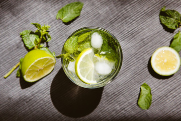 Lemonade or mojito on black background with lime, mint and ice 